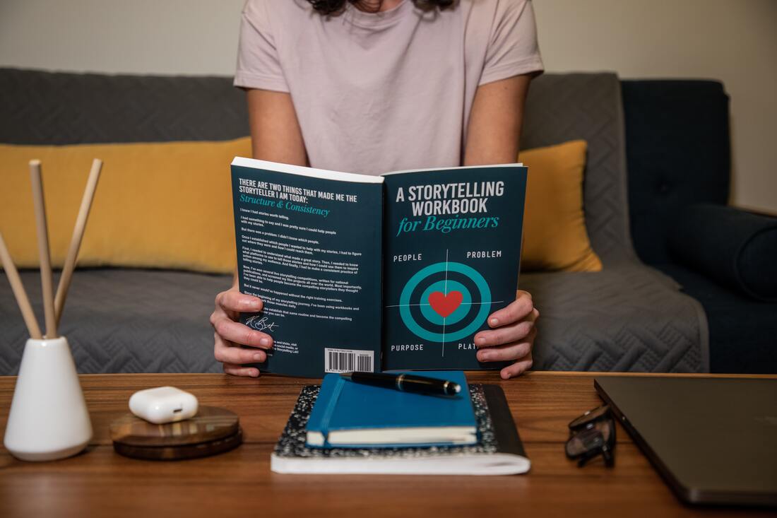 Image contains a woman reading a book about storytelling workbook