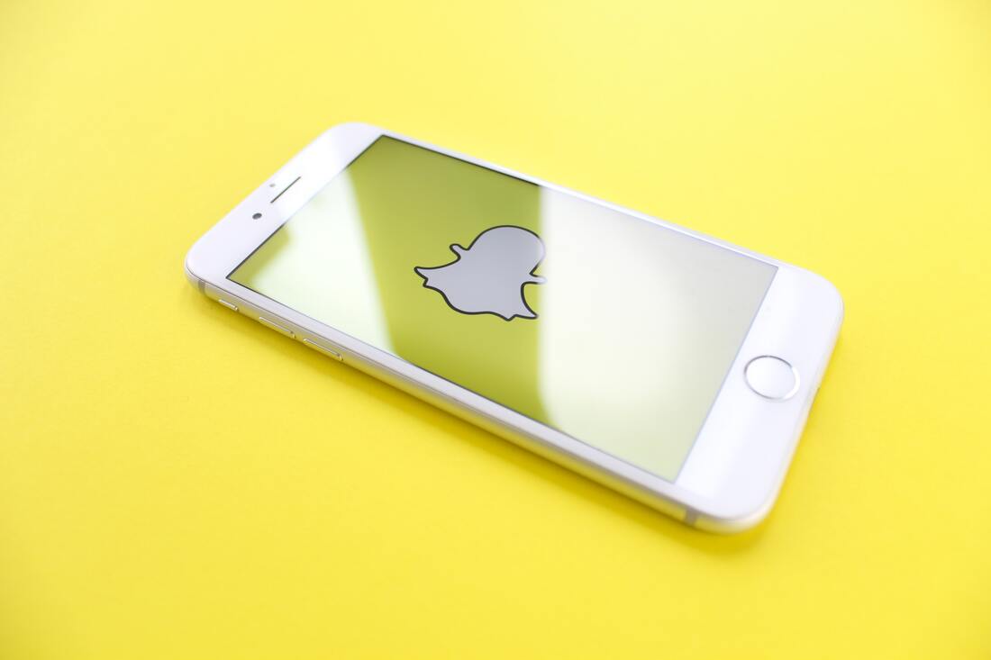 Image contains an iPhone displaying the snapchat logo