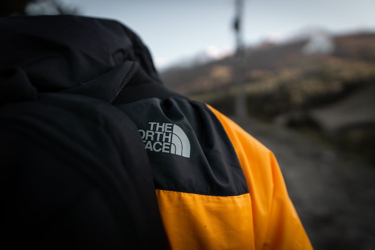 Image for the North Face history: a North Face coat, from behind, that displays the logo. It's black and yellow